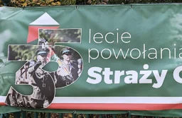 Fragment zielonego baneru z jubileuszowym logo „35” i napisem „lecie powołania Straży Granicznej”, na logo funkcjonariusze z pocztem sztandarowym