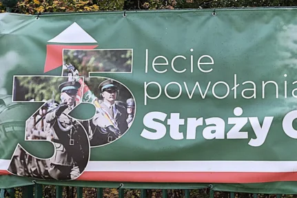 Fragment zielonego baneru z jubileuszowym logo „35” i napisem „lecie powołania Straży Granicznej”, na logo funkcjonariusze z pocztem sztandarowym