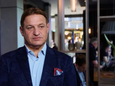 Prof. Jacek Męcina w granatowej marynarce i błękitnej koszuli, w tle wnętrze kawiarni