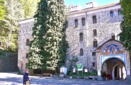 Mur Monastyru Rylskiego z freskiem nad bramą wejściową, w dole fotograf z aparatem