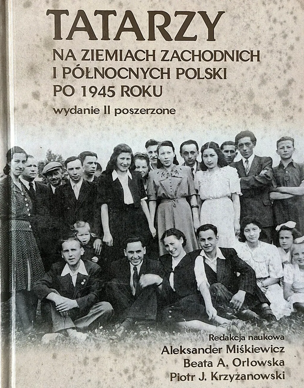 Okładka książki o Tatarach na ziemiach zachodnich i północnych Polski po 1945 roku, na zdjęciu archiwalna grupa młodych ludzi na trawie